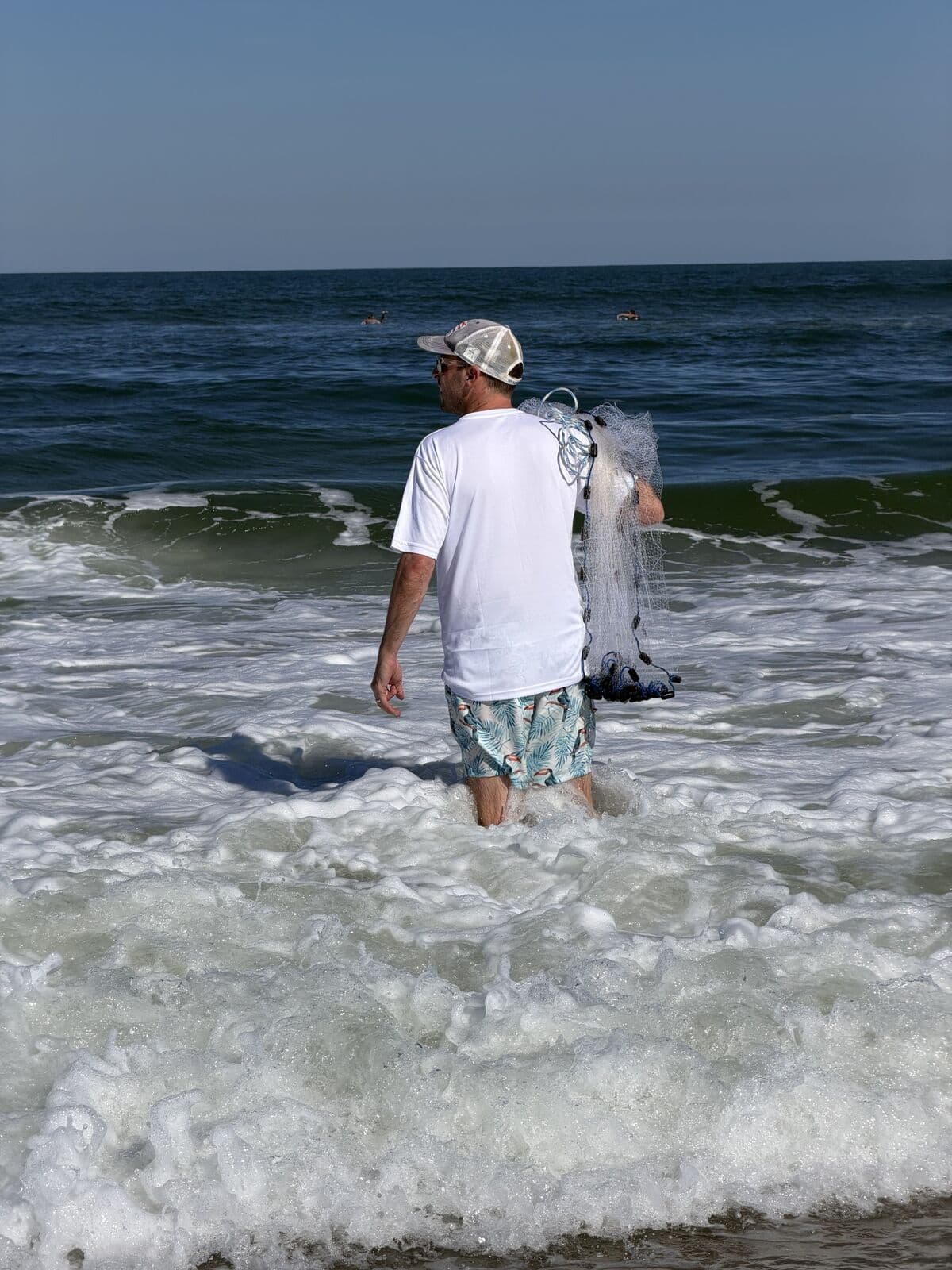 Wading into the Atlantic surf with a cast net over one shoulder
